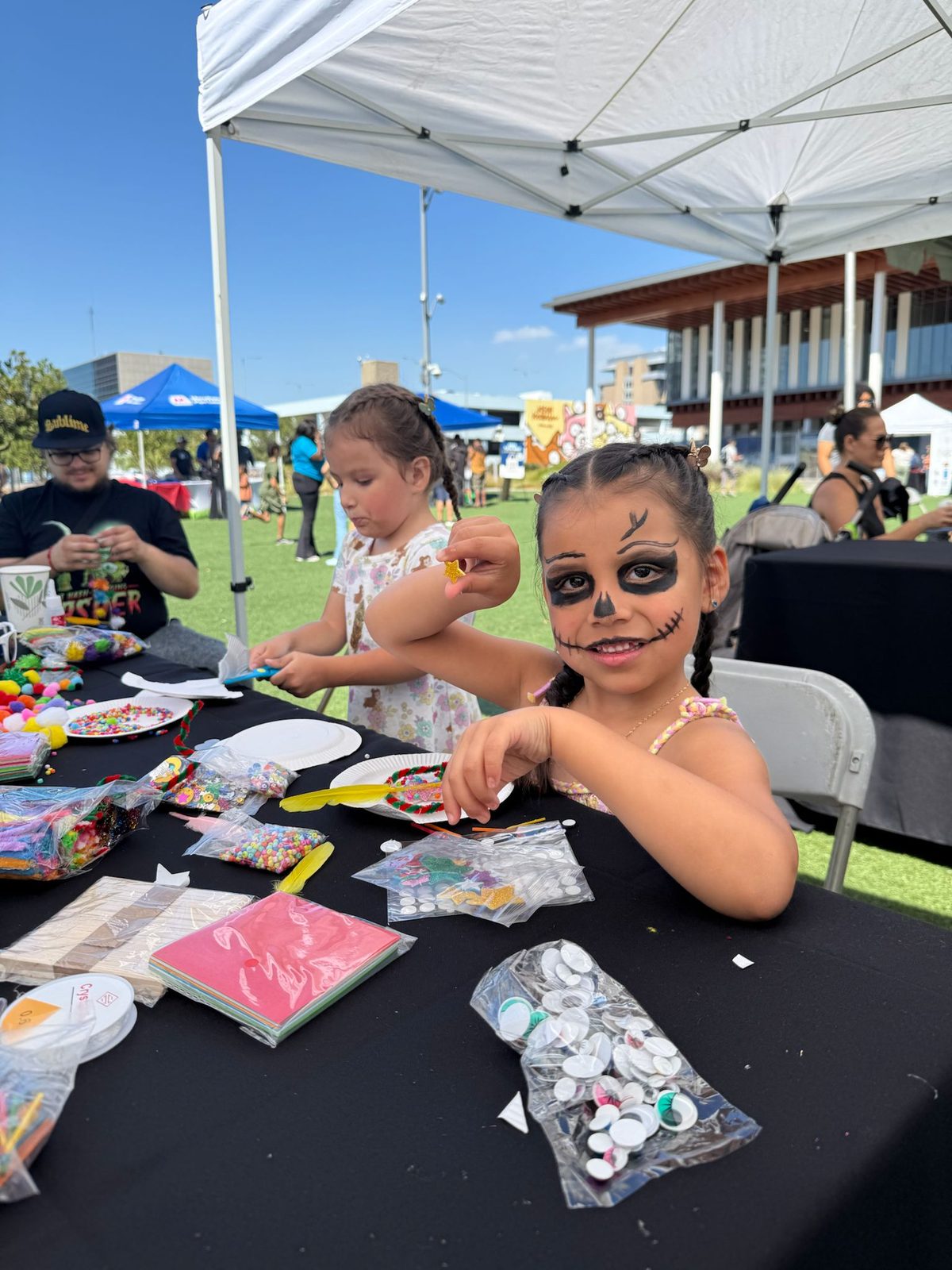Kids making crafts at a table full of beads, feathers, and paper.
