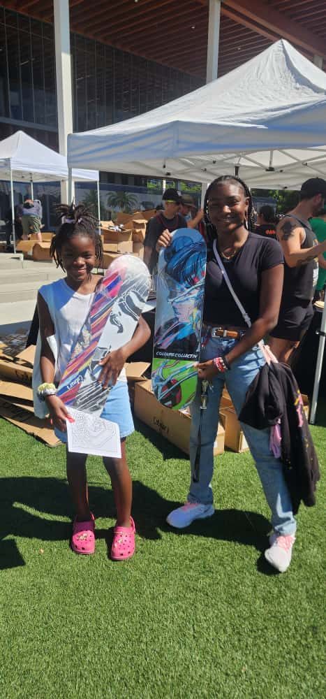 A young skater and a volunteer holding new skateboard decks.