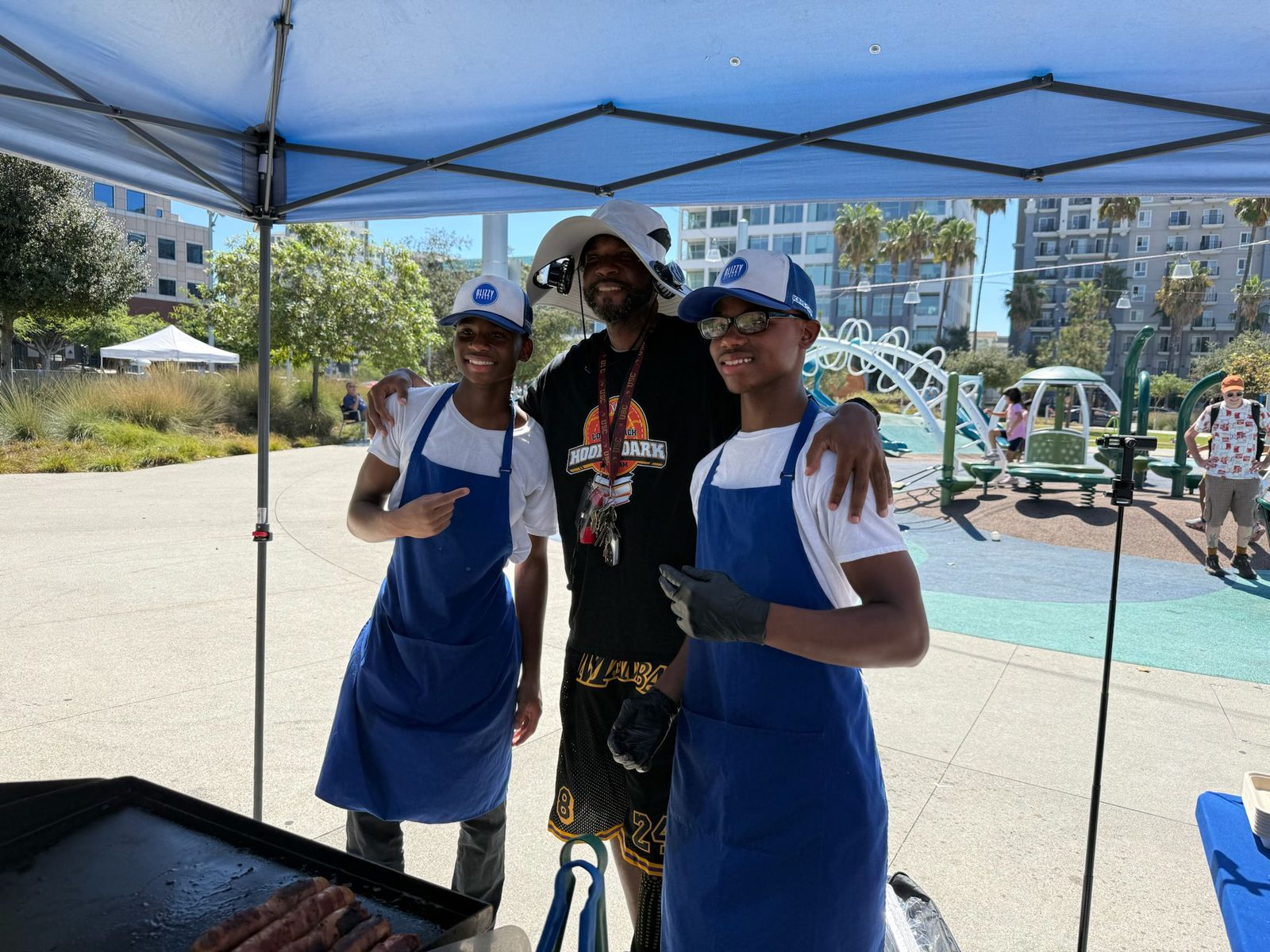 Two teen volunteers in aprons at the grill with a DIG LIFE mentor.