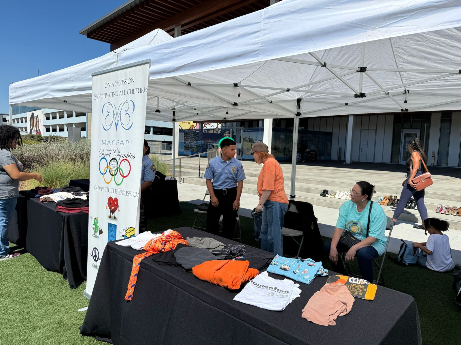 Tables of free clothing and shoes with community members browsing.